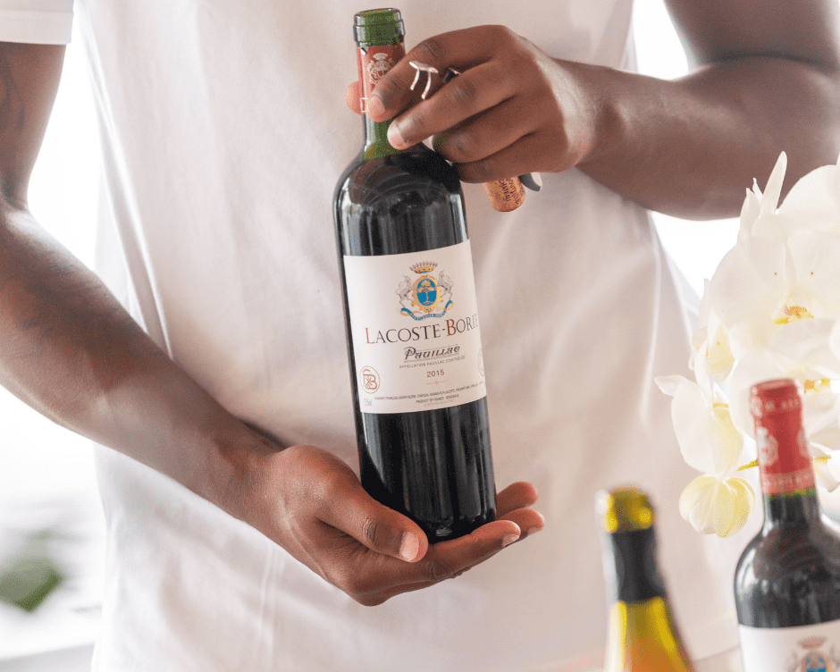 A waiter brings a bottle of red wine from Lacoste Borie