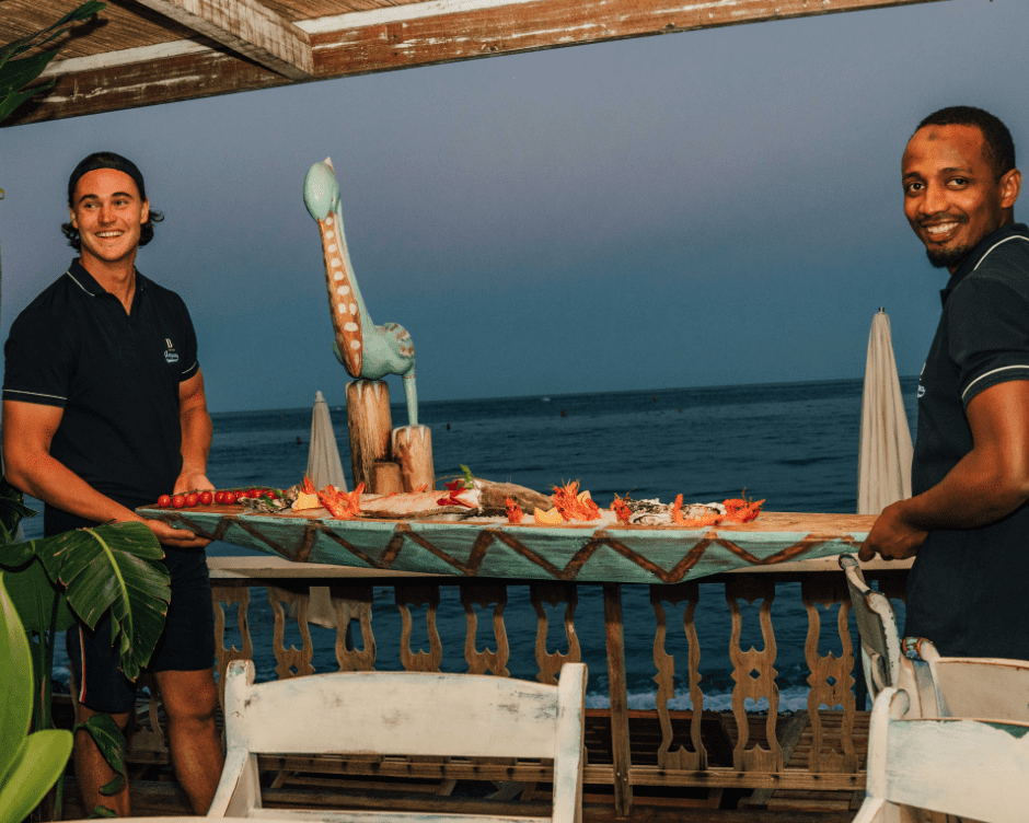 Two waiters bring a seafood platter in the form of a boat
